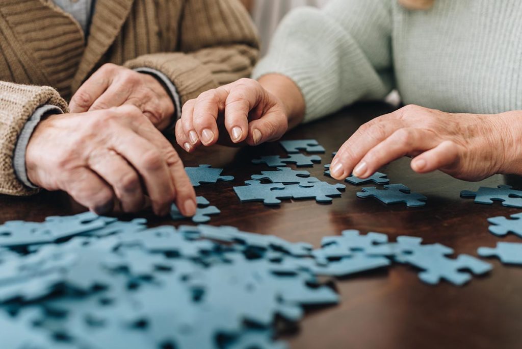 old people putting together puzzle discussing moving into senior memory care