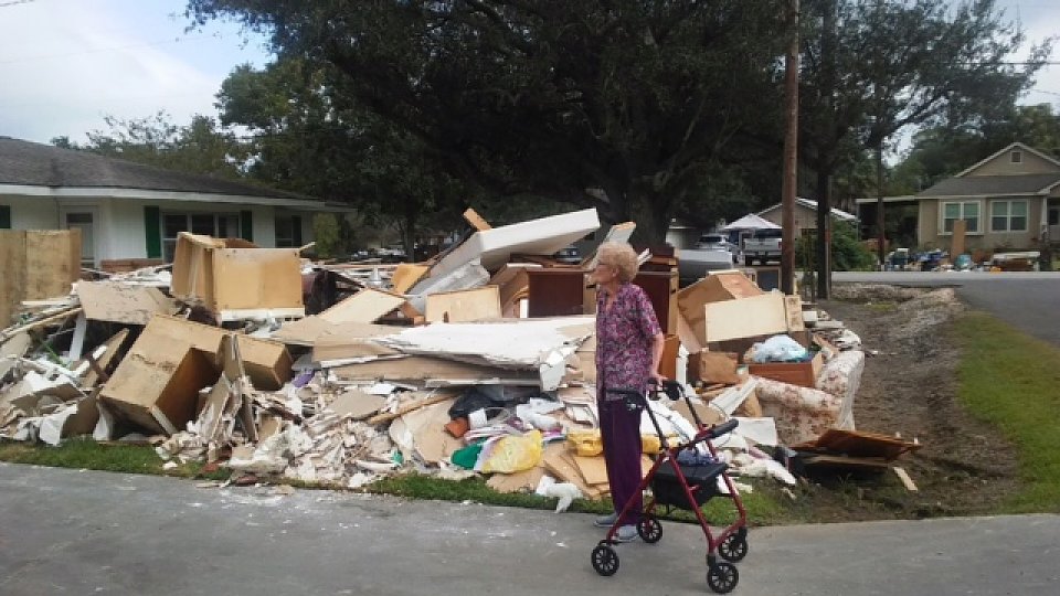 old lady standing in front of trash pile