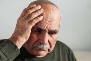 man holding head and showing signs of alzheimer's