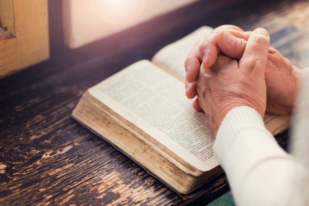person's hands on bible learning the role of chaplains in senior living