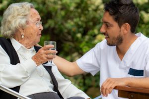 Senior drinking water in respite care and talking to staff