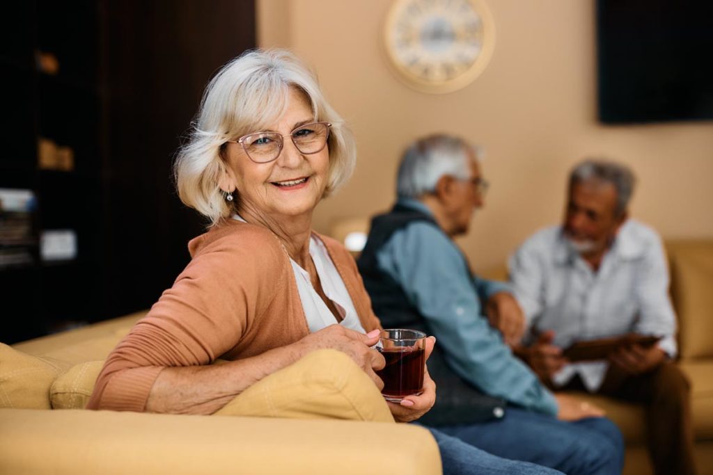 Senior sitting on couch enjoying drink inside a senior living community