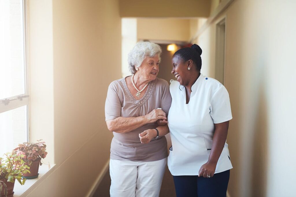 Health professional walks with senior in assisted living facility as they discuss memory care