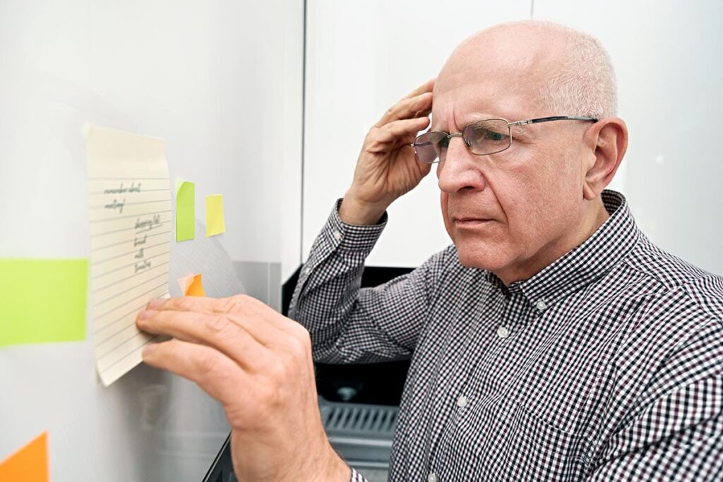 Senior looks at sticky notes as he wonders if it is time for senior memory care