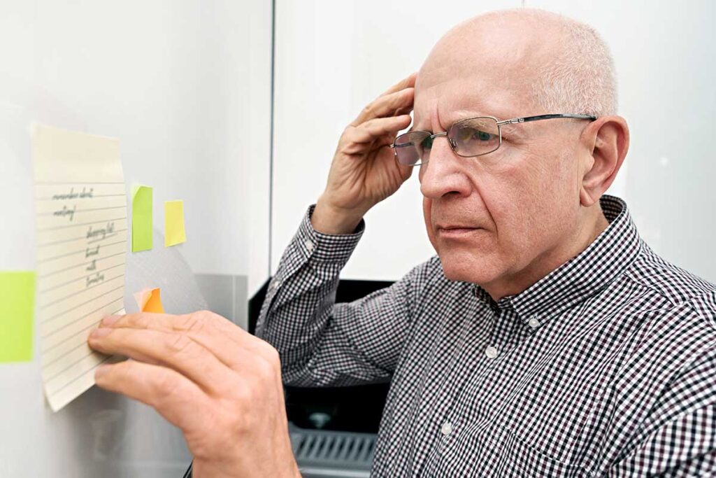 Senior man struggles to read sticky notes as his family considers assisted living for him