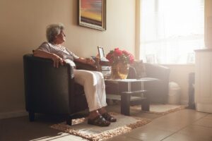 Woman sits in chair in early morning light, thinking about senior speech therapy benefits