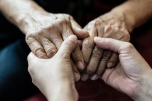 Person holds hands with senior, wondering "what age does dementia start?"