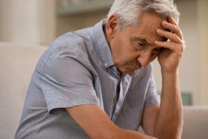 Distraught man rests head in hand and thinks about Alzheimer's life expectancy