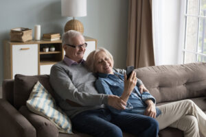 Senior couple cuddles up on couch after discovering the benefits of downsizing in retirement