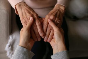 Woman holds hands with senior mom as they discuss the cost of memory care in Texas
