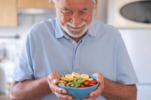 Man holds a bowl of fruit after learning about senior nutrition for health aging