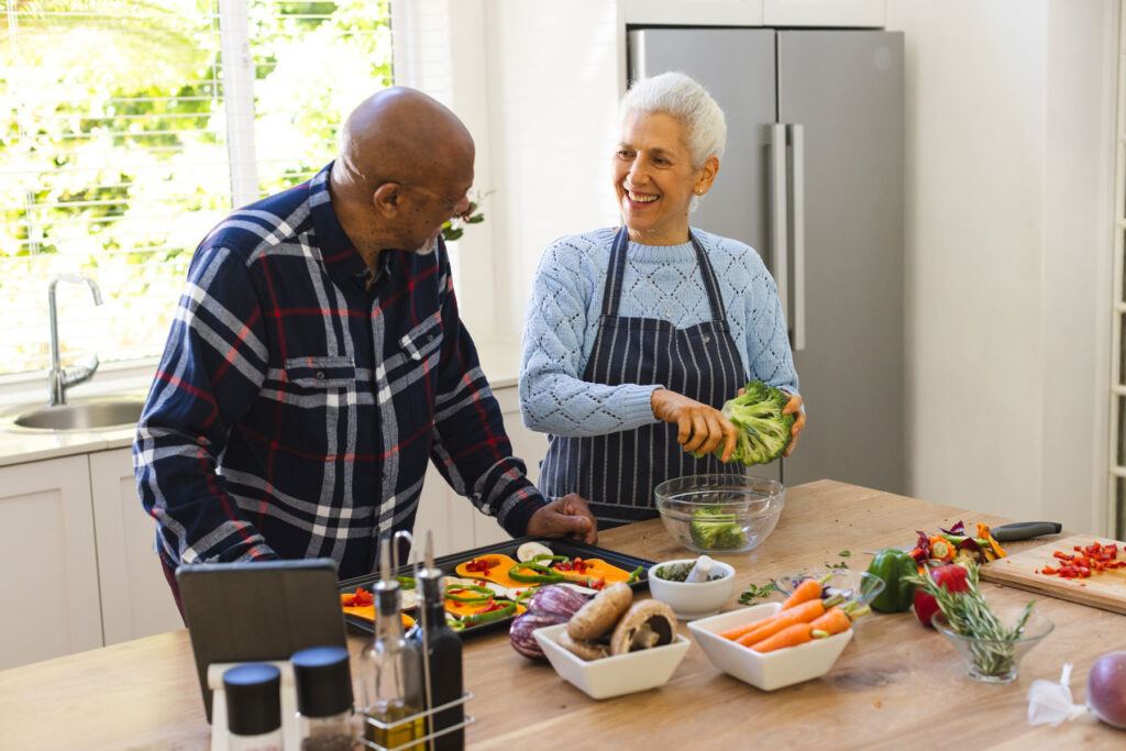 Two seniors cook together and chat about foods that help brain health