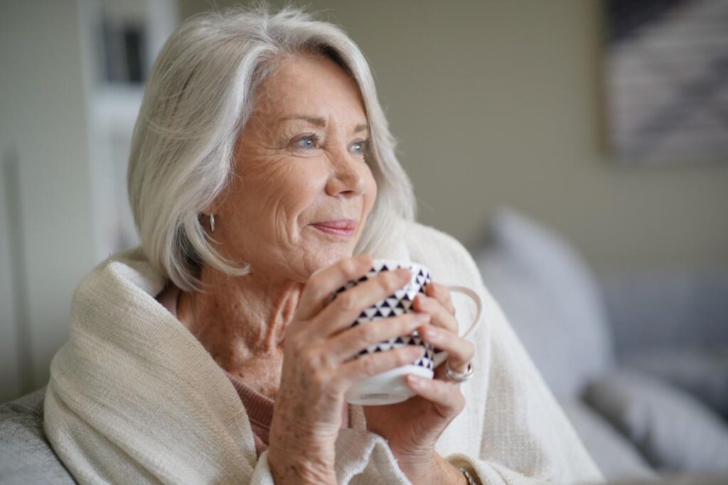 A woman holds a cup of coffee and enjoys the safety features in senior independent living.