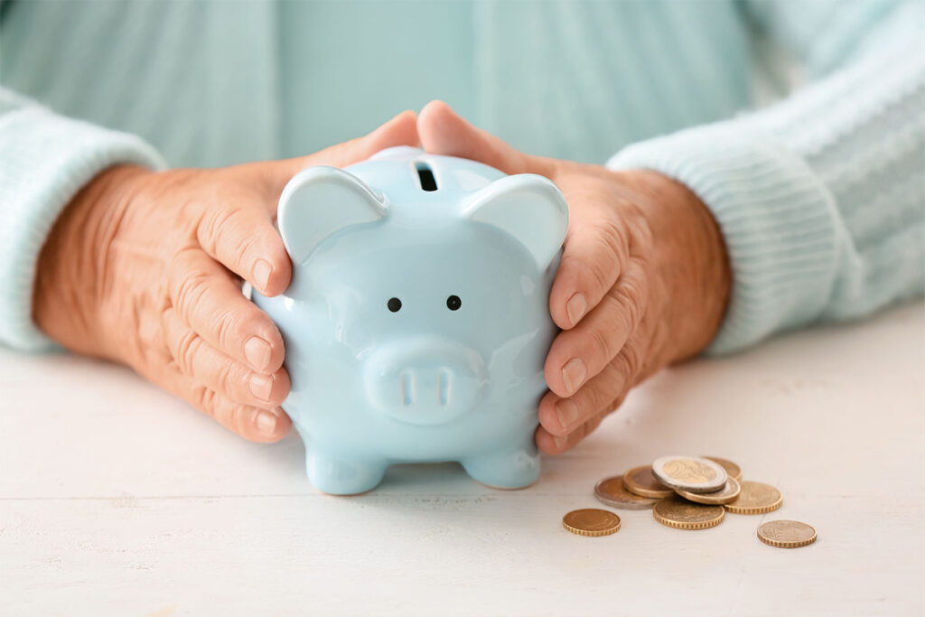 A senior adult holds a piggy bank and worries about how the affordable housing crisis for seniors will impact their retirement.