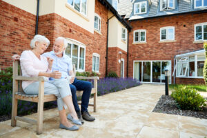 Senior couple sits on bench after discussing reasons to move to senior living